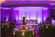 View of Grand Ballroom Tables and Stage Decorated and Lit in Purple