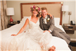 Bride and Groom Laughing Seated on Hotel Room Bed